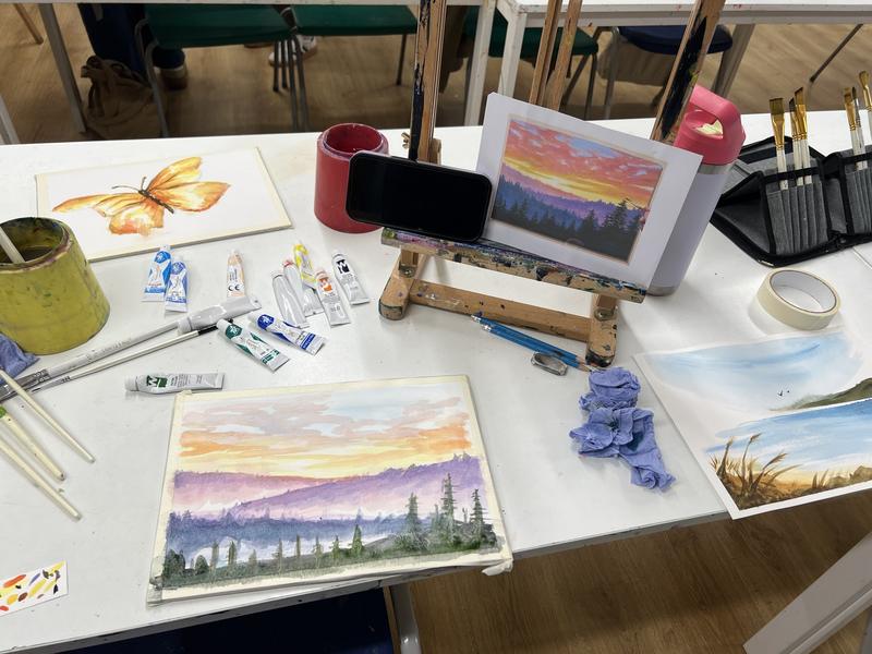 Watercolour sunset landscapes in progress on a studio table