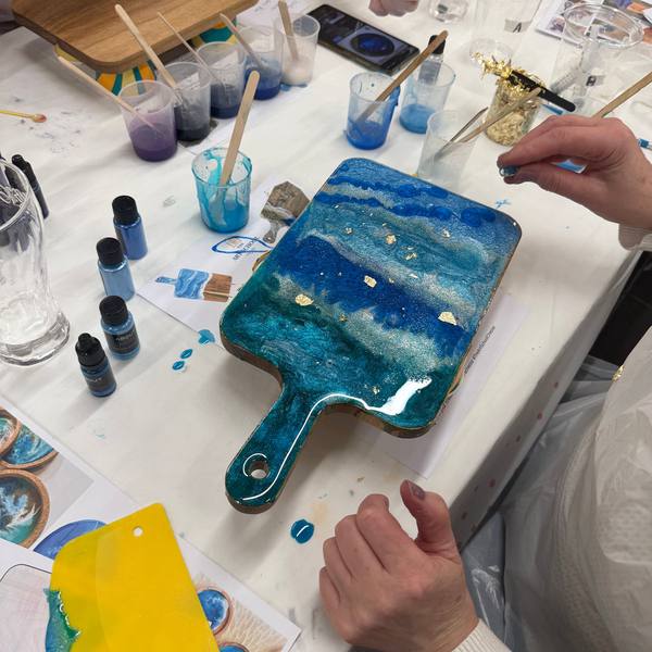 A blue and teal resin paddle board with workshop materials